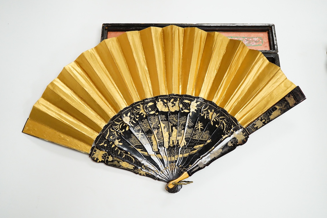 Four 19th century Chinese gilt-decorated black lacquer fans with figure painted leaves, two cased, largest 41cm